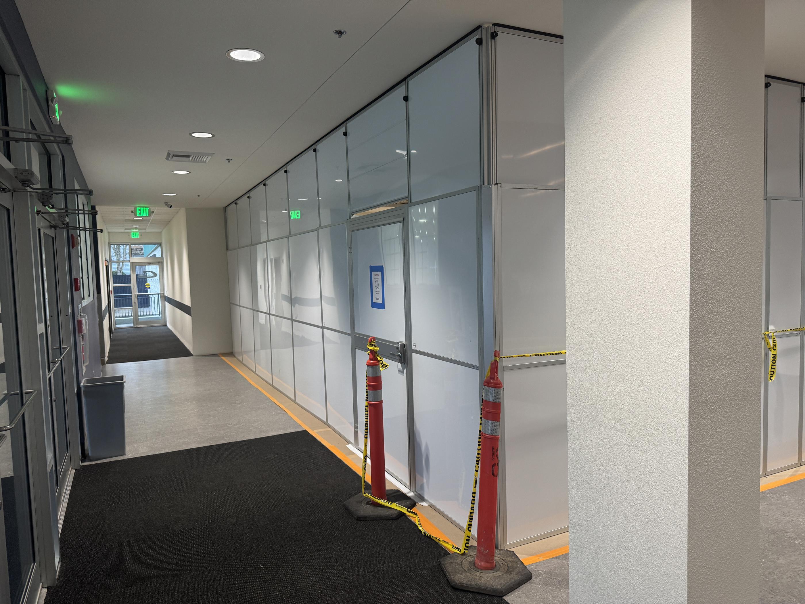 Modular containment wall separating renovation work from customer access inside an active athletic club