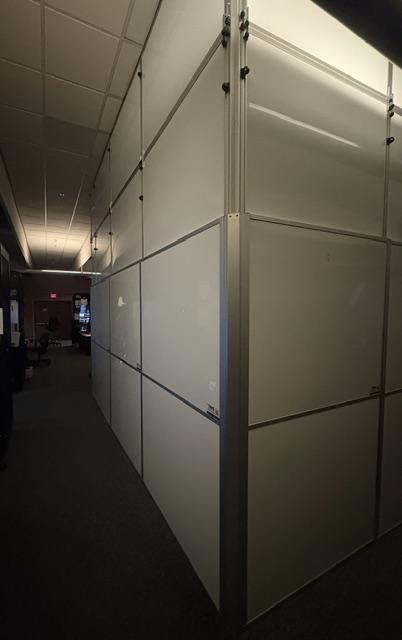 Modular temporary wall creating a secure work zone inside an operational FAA control room.