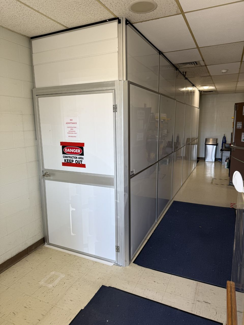 Dust-tight temporary construction walls with secure access door installed for federal facility renovation containment