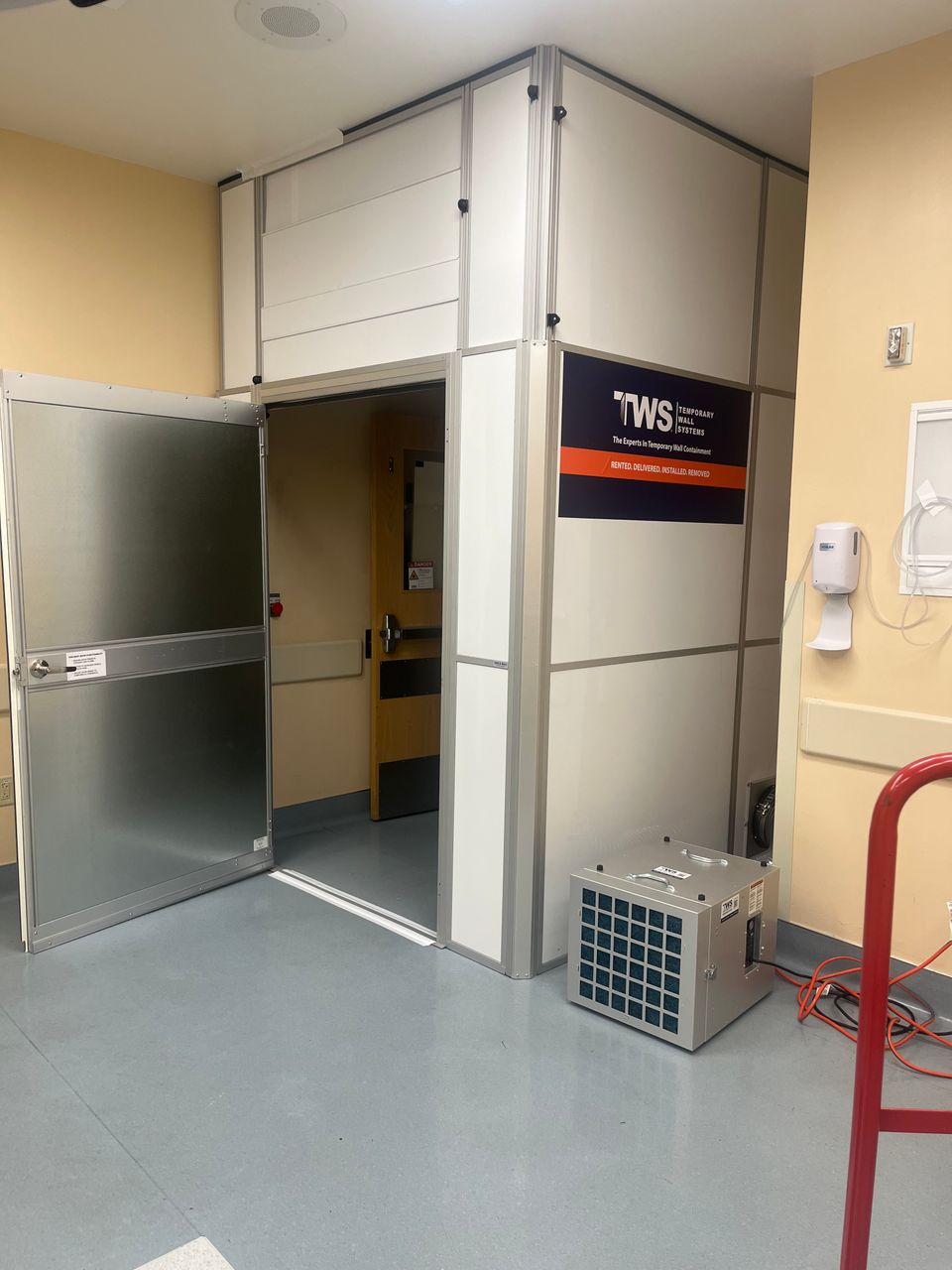Level V ICRA modular hard wall containment with an anteroom and HEPA-filtered negative air unit installed for operating room renovations at Kootenai Health.