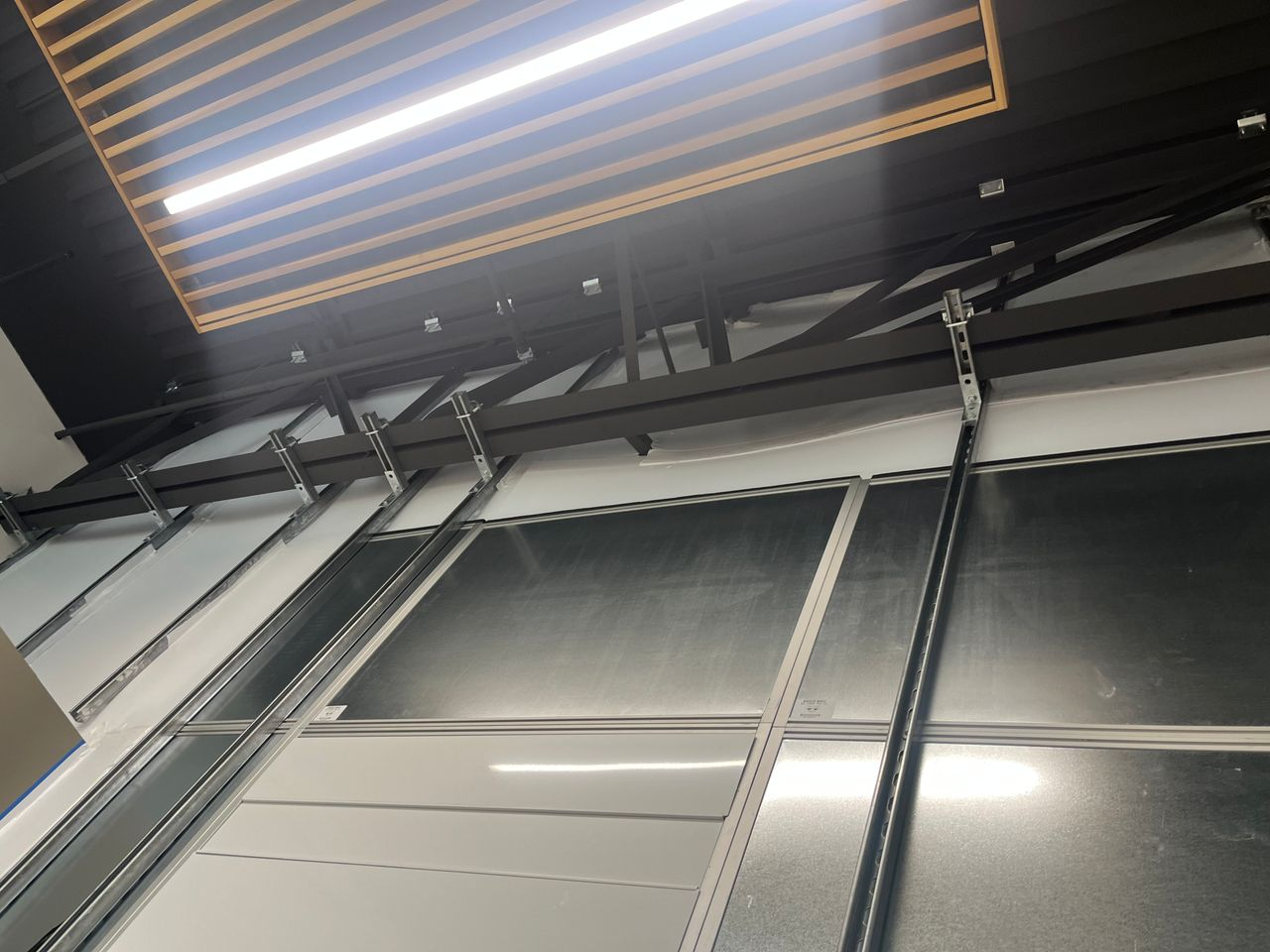 Structural steel strut supports stabilizing a 19-foot floor-to-deck modular hard wall containment system installed by Temporary Wall Systems for a healthcare clinic expansion.