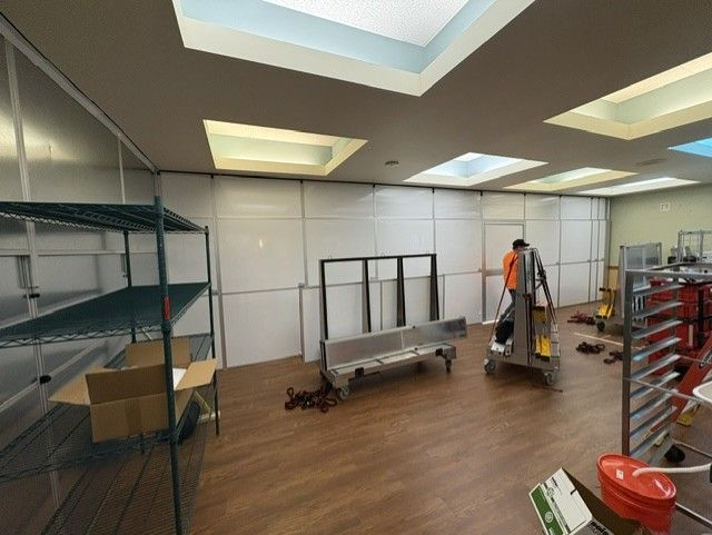 Large-scale healthcare containment installation creating a temporary cafeteria workspace with freestanding temporary walls during hospital kitchen construction.