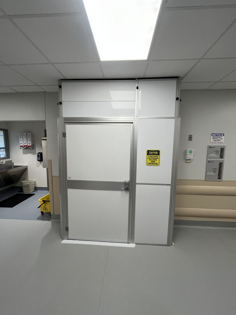 Temporary wall containment installed in a hospital corridor to support operating room refresh work while maintaining emergency department operations.