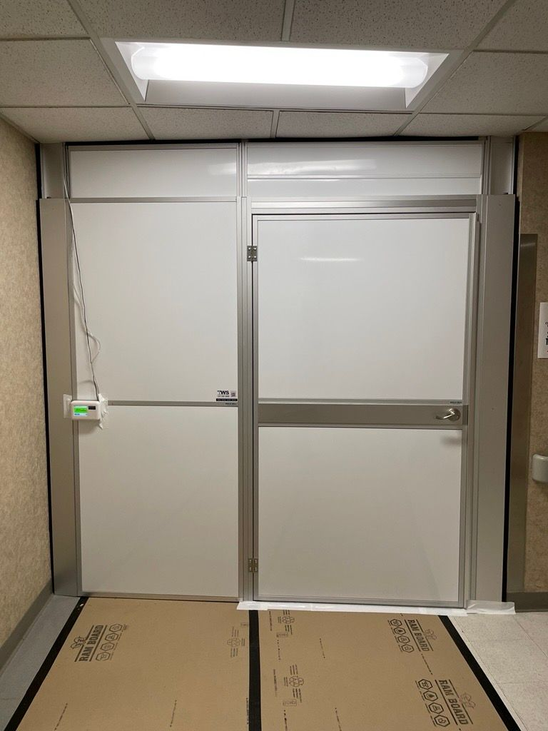 Healthcare and education construction containment wall with integrated access door and negative air controls installed by Temporary Wall Systems.