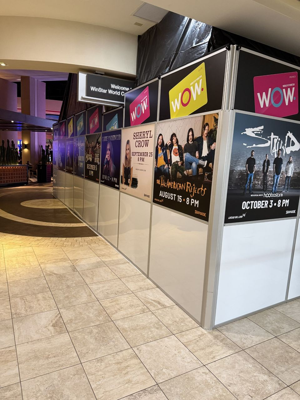 Modular hard wall containment system with branded graphics supporting occupied casino renovation and guest wayfinding at WinStar World Casino Resort.
