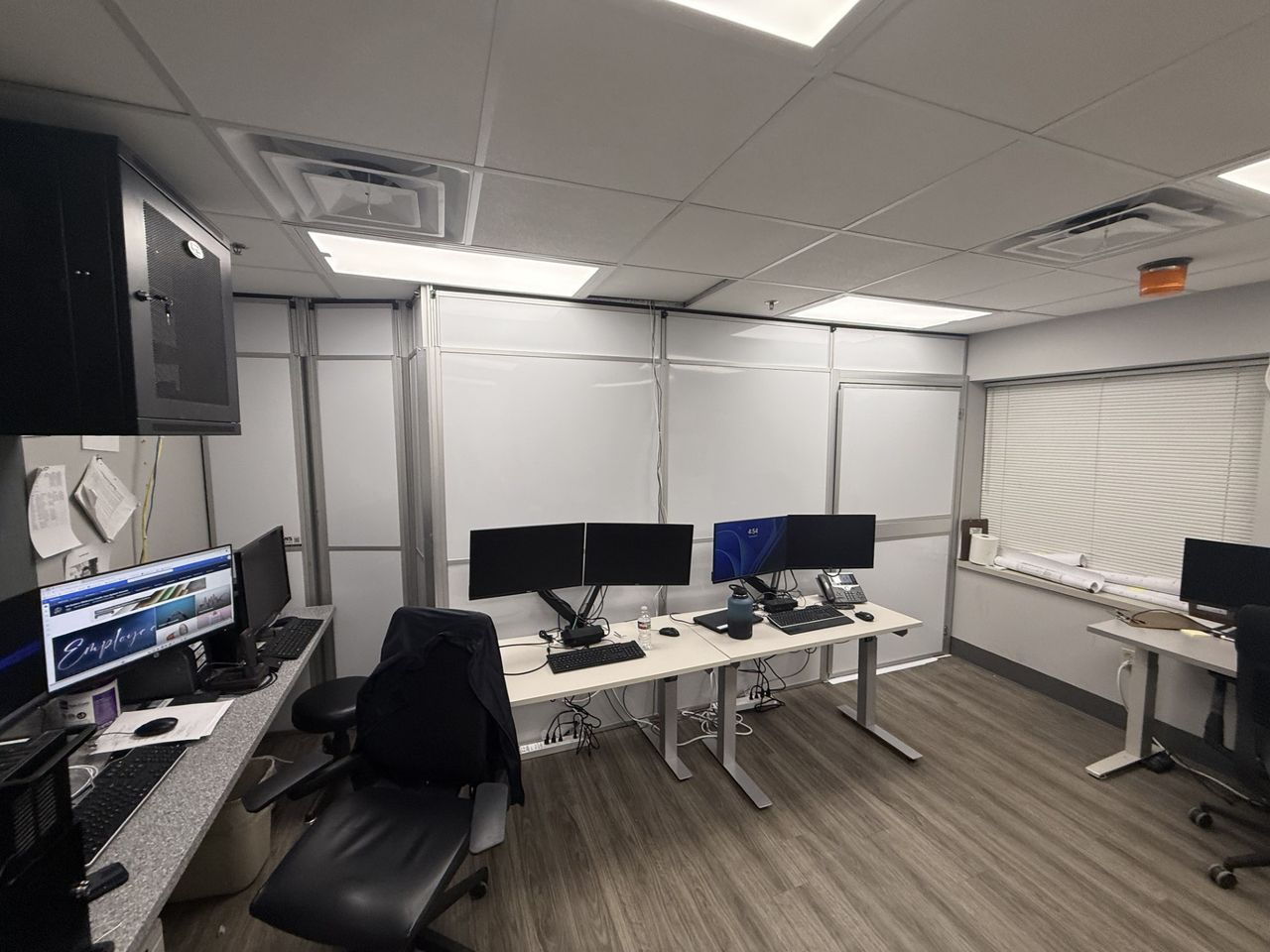 Temporary construction wall system with integrated access door providing construction containment adjacent to an active monitoring and security workspace.
