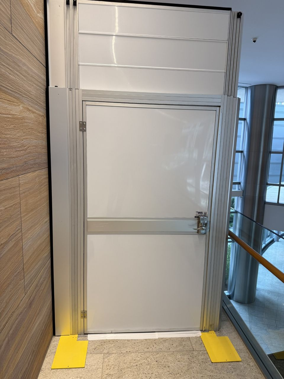 Temporary Wall Systems containment door installed within a modular hard wall containment system protecting occupied office tower spaces during a tenant improvement renovation.