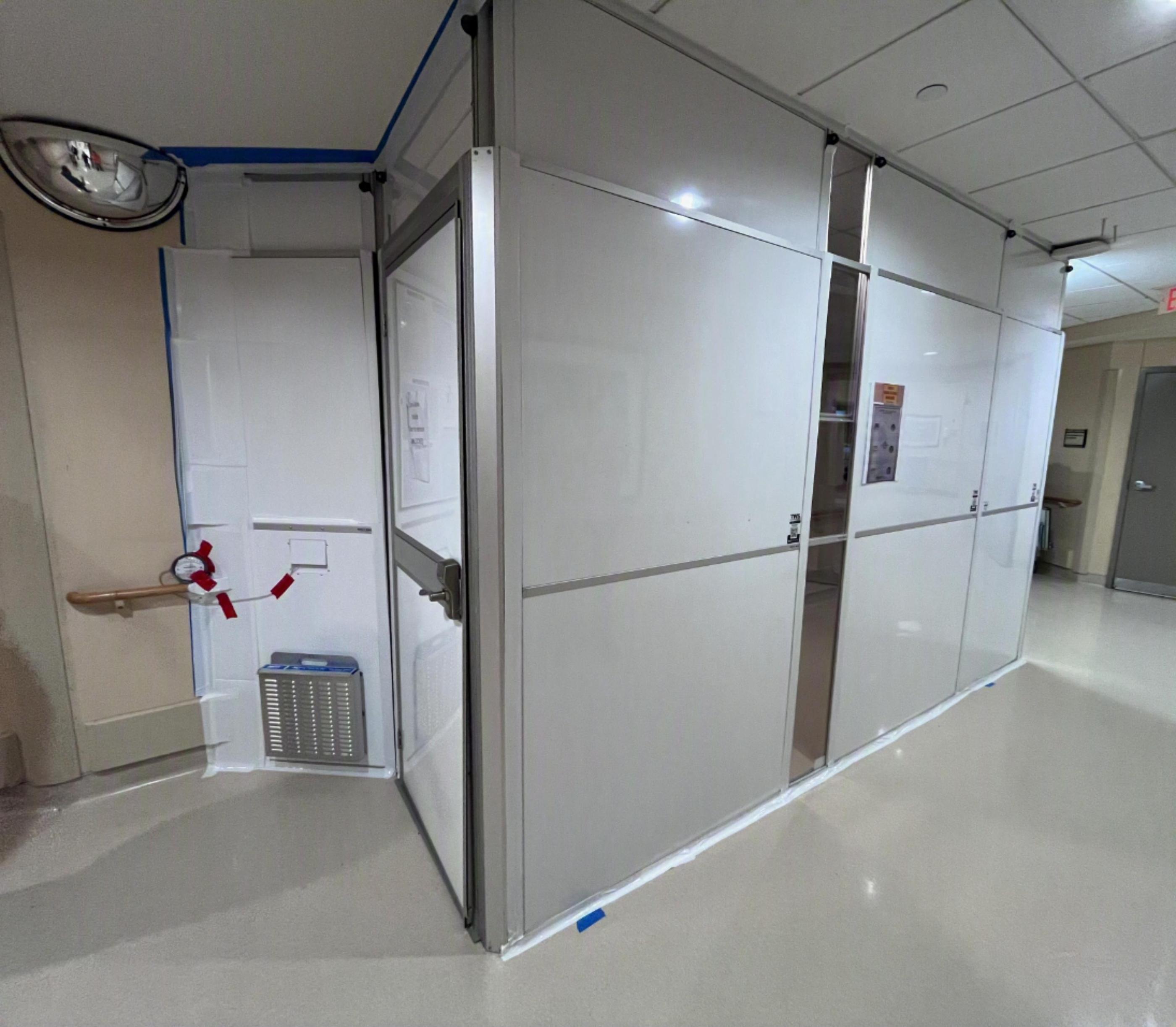 Custom ICRA containment with an access door, exhaust panel, and clear panel preserving visibility of medical gas controls.