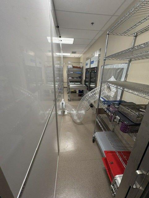 Healthcare containment corridor with modular temporary walls, negative air ducting, and controlled access inside sterile processing renovation area