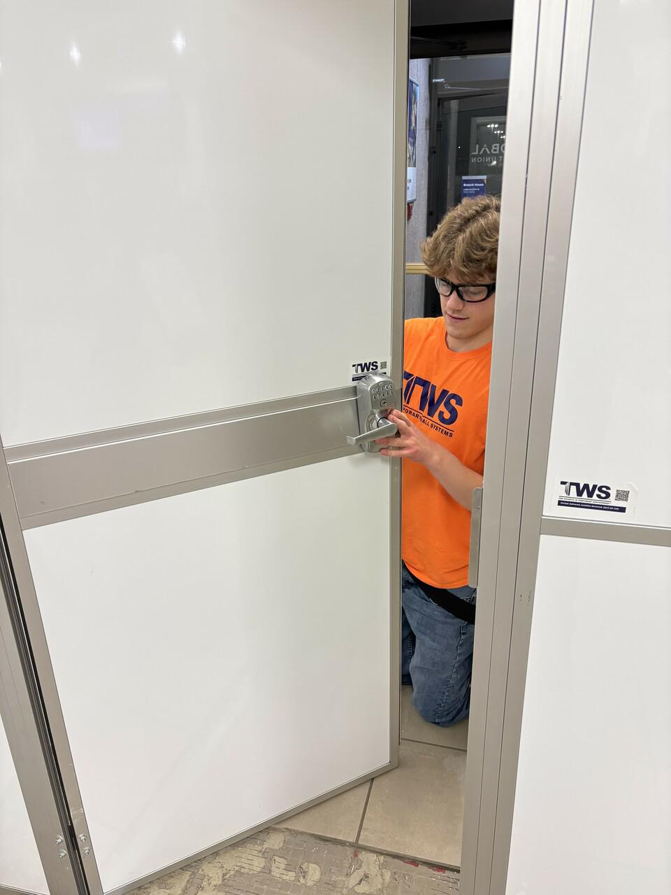 Technician installing secure access door within Temporary Wall Systems modular hard wall containment during occupied bank renovation in Anchorage, Alaska