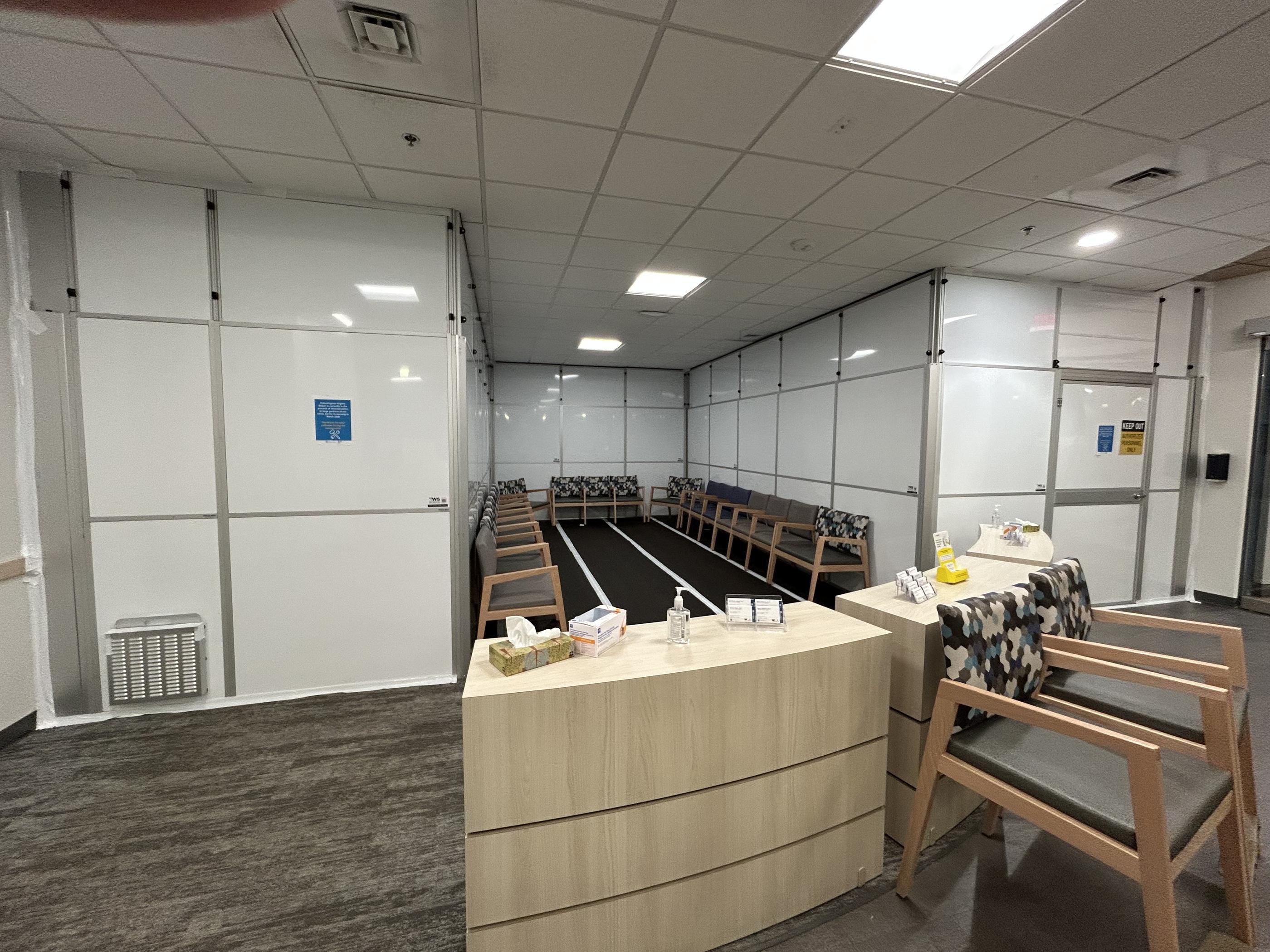 Reconfigured hard-wall containment providing additional patient seating space around an active medical reception area.