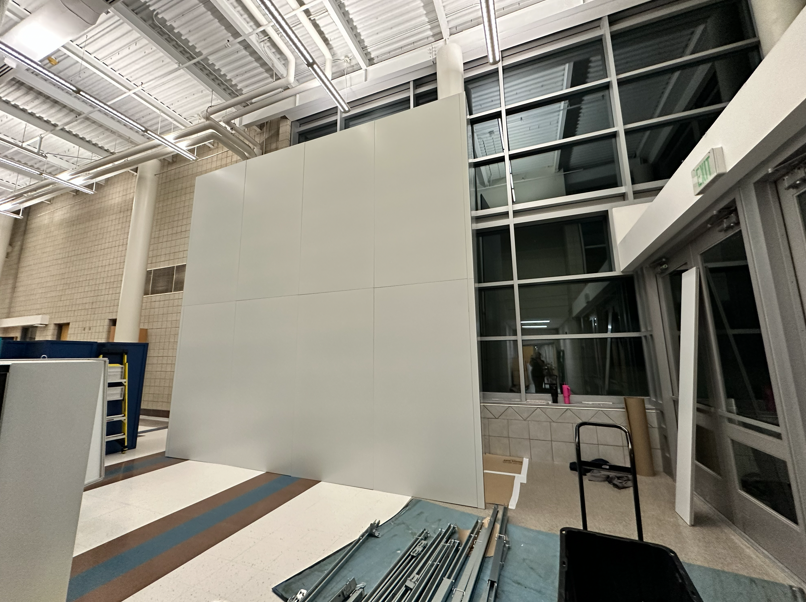 Tall temporary wall containment installed in a school atrium, providing safe separation between renovation work and daily educational operations.