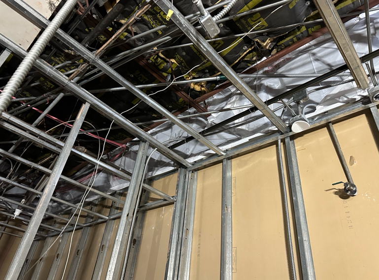 Healthcare construction containment extending to the structural deck using fire-rated plastic and sealed framing to create a complete dust and asbestos containment barrier.