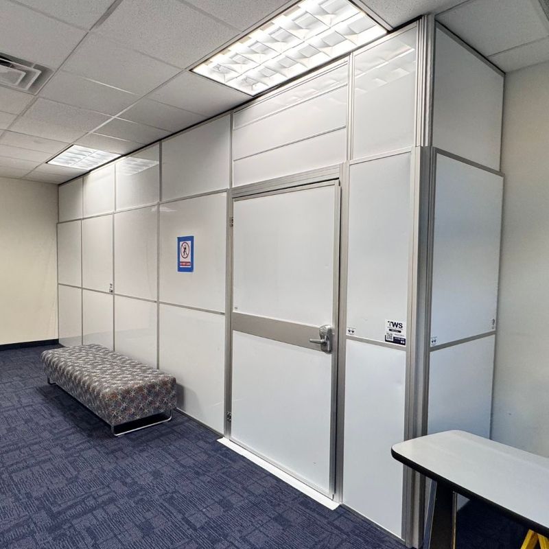 temporary walls on a blue carpet with a grey bench in front of the walls