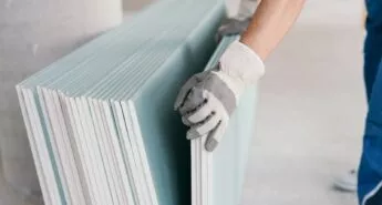 Close up of someone wearing white and grey work gloves moving a stack of Temporary Wall Systems modular walls.